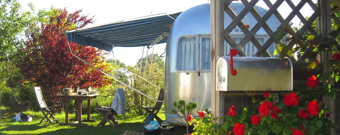 Une caravane ancienne installée dans un jardin.