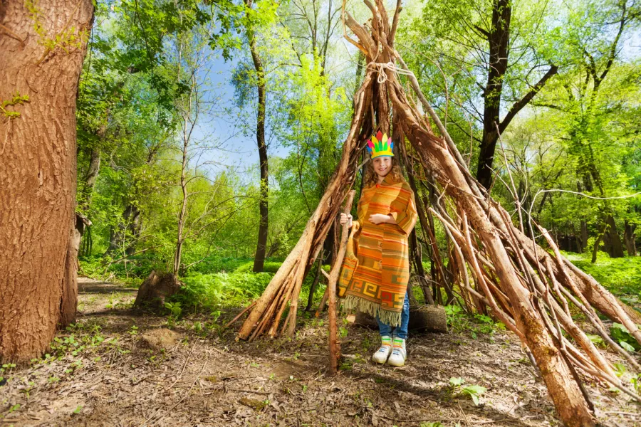 Un enfant fabrique une cabane dans la forêt.