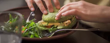 Toutes folles des nouvelles tendances food ! Une personne mangeant un hamburger végatal.