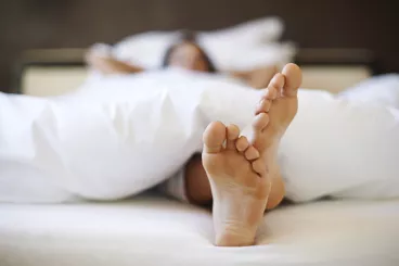 Ce matin, je reste au lit ! Une femme se repose dans son lit lors d'une grasse matinée.