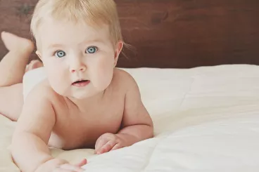 Optons pour une lessive adaptée à la peau des bébés Un bébé à plat ventre sur un lit
