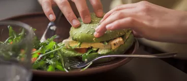 Une personne mangeant un hamburger végatal.