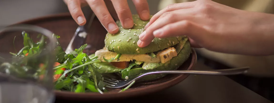 Toutes folles des nouvelles tendances food ! Une personne mangeant un hamburger végatal.