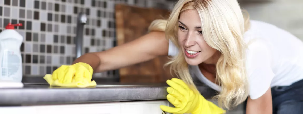 Une femme nettoye sa cuisine avec un produit d’entretien.