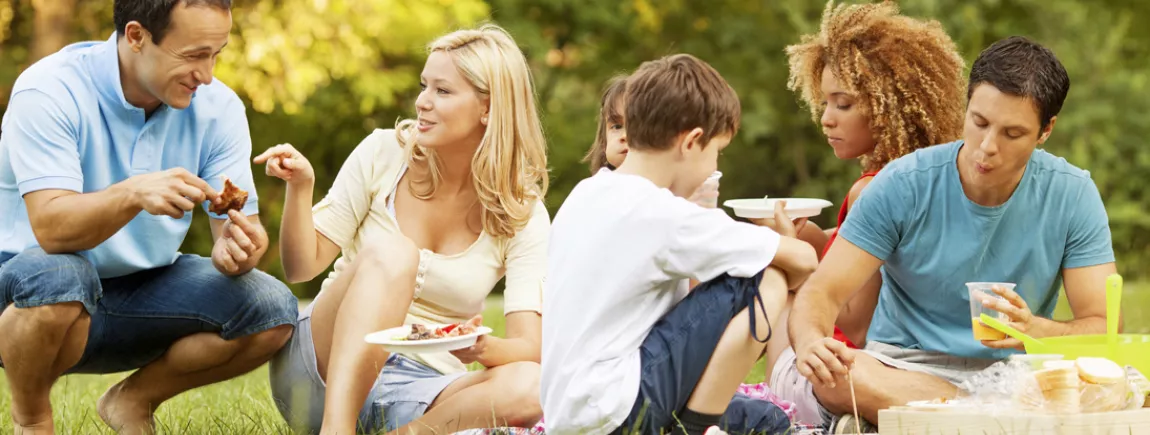 Idées gastronomiques pour un pique-nique 100% pratique Un groupe de gens partagent un pique-nique dans un parc.
