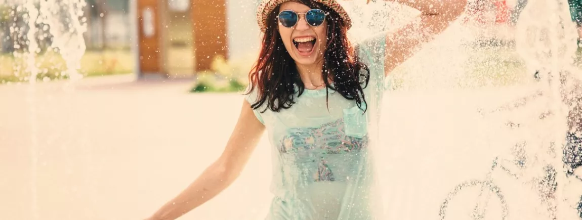 Malin : le kit anti-canicule ! Une femme se rafraichit dans des jets d’eau