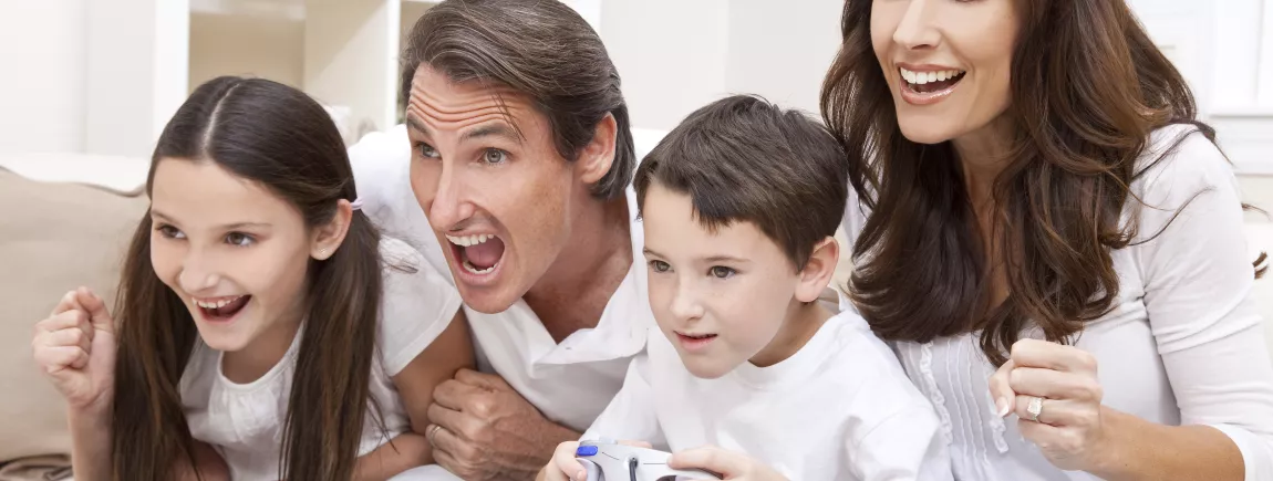 Jeux-vidéos en famille : et si vous sautiez le pas ? Famille s’amusant et partageant un moment convivial en jouant aux jeux-vidéos